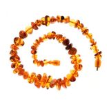 Graduated row of amber beads, the sixty-two irregularly shaped tumbled beads varying for colour