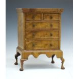 Early 20th Century Queen Anne style crossbanded walnut miniature chest on stand, fitted two short