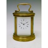 Large oval brass cased carriage clock, the white enamel dial with Roman numerals, movement