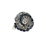 Sapphire and diamond cluster ring, the white mount stamped '750', of whorl design, with a row of