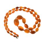 Graduated row of oval amber beads, the forty-seven beads of approximately 10mm to 27mm in length,