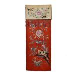 Chinese embroidered silk wall hanging decorated with a cat and birds amongst foliage on a red