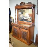 Edwardian walnut sideboard, the raised bevelled mirror panel back having a carved pediment and