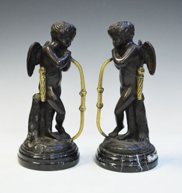 Pair of reproduction bronzed figures, each depicting Cupid and standing on a marbled slate socle