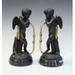 Pair of reproduction bronzed figures, each depicting Cupid and standing on a marbled slate socle