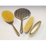 Four silver backed dressing table items comprising: hand mirror, hand brush and pair of clothes