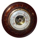 Early 20th Century circular carved walnut framed aneroid barometer, the off-white dial with a