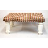 Large rectangular stool having an upholstered top and standing on heavy turned and chamfered