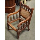 Late Victorian child's walnut elbow chair having a split cane back, scroll arms and standing on