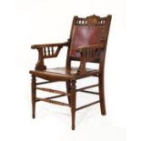 Edwardian oak framed open arm elbow chair standing on turned supports united by stretchers