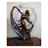 Reproduction Art Nouveau style table lamp with stained glass circular shade behind bronzed Art