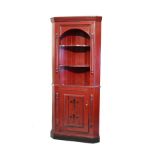 Dark red and black painted pine standing corner cupboard, the upper section fitted three open