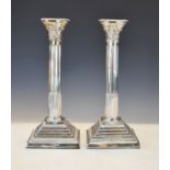 Pair of Elizabeth II silver Corinthian columned candlesticks, each standing on a square stepped