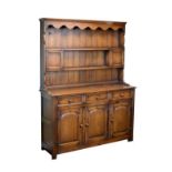 Old reproduction oak high dresser with wavy valance over two shelves and planked back, the lower