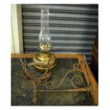 Wrought iron wall mounting lamp bracket with brass bodied paraffin lamp beneath glass chimney