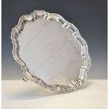 George VI silver salver having a piecrust edge and standing on triple scroll feet, presentation