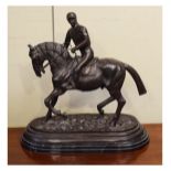 Bronze equestrian figure depicting a jockey on horseback, standing on a marbled black slate base