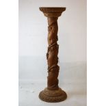 Carved fruitwood torchère or vase stand with circular top over barley twist column, carved with
