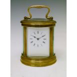 Large oval brass cased carriage clock, the white enamel dial with Roman numerals, movement with