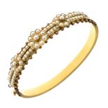 Edwardian split pearl set gold hinged bangle, unmarked, the frontispiece with three graduated flower