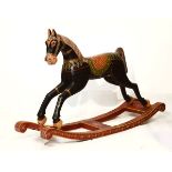 Painted wooden rocking horse with carved mane, red and green decorated gilt bridle, polychrome