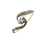 Unmarked yellow metal ring set solitaire diamond, the crossover mount with diamond shoulders, size