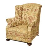 Early 20th Century wing back easy armchair upholstered in floral patterned brocade and standing on