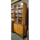 1920's period walnut veneered bookcase on cabinet, the glazed upper section enclosing four