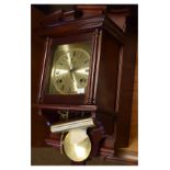 Mahogany stained reproduction wall clock by Highlands, together with another example by Hermle