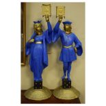Pair of painted spelter figural candlesticks, each modelled as a robed figure holding aloft a socket