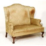 Early 20th Century two seater wing back settee upholstered in gold brocade and standing on