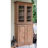 Stripped pine two stage bookcase cabinet with fluted cornice over glazed upper section enclosing
