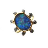 Unmarked yellow metal ring set large central oval opal panel within border of eight spaced diamond
