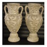 Pair of plaster garden urns of two handled ovoid form with relief moulded foliate decoration on