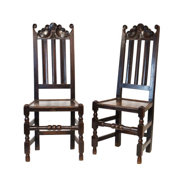 Pair of early 18th Century carved oak hall chairs, each having a scroll carved crest rail over three
