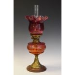 Late 19th/early 20th Century oil lamp having cranberry glass reservoir and shade, on brass flared