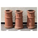 Three terracotta coloured stoneware chimney pots, each of cylindrical design with fluted upper