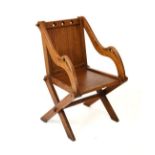 Late Victorian pitch pine Gothic Glastonbury elbow chair having pierced trefoil crest and arms, hard