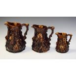 Set of three graduated treacle glazed pottery relief jugs, each decorated with the Babes In The Wood