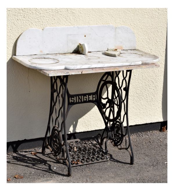 Singer sewing machine on cast iron treadle base, fitted with a grey veined marble top, together with
