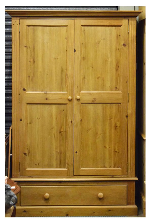 Modern pine wardrobe having a pair of two panelled doors over base drawer between fluted uprights on