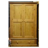 Modern pine wardrobe having a pair of two panelled doors over base drawer between fluted uprights on