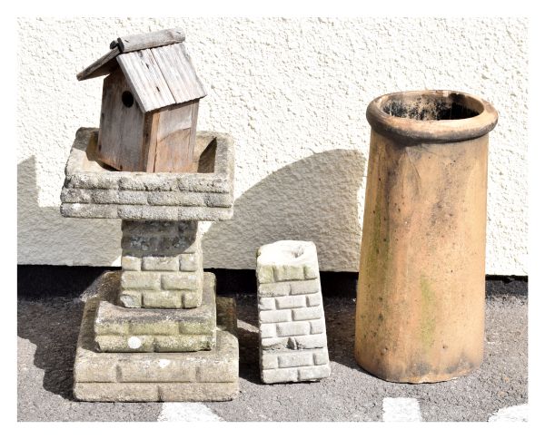 A pale terracotta coloured cylindrical chimney pot, a reconstituted stone birdbath of stepped design