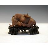 Japanese carved hardwood figure depicting a recumbent buffalo having a hat resting on its back and