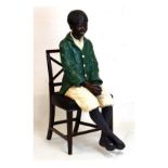 Life-size plaster figure of a seated African American boy, 119cm high Condition: