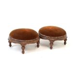 Pair of Victorian carved walnut circular footstools, each having a stuffed seat upholstered in red