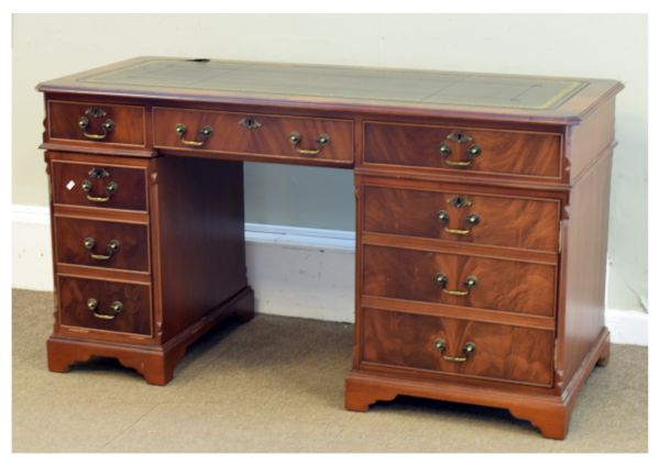 Reproduction mahogany twin pedestal desk having a gilt-tooled green skiver within moulded canted