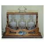 Early 20th Century oak three bottle tantalus with silver plated handle and mounts, the front of