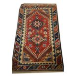 Wool rug having two geometric lozenge on a red ground with multi border, 135cm x 73cm approx