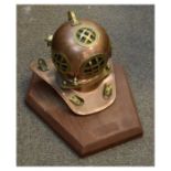 Brass-mounted copper model diving helmet on irregular hexagonal wooden base Condition: